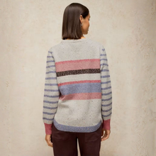 Load image into Gallery viewer, A woman viewed from behind wearing a heather gray knit sweater with horizontal stripes in dusty pink, lavender, and dark brown, paired with dark brown pants, set against a textured beige wall.
