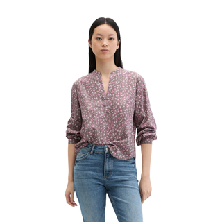 Woman wearing a patterned blouse and jeans on a white background