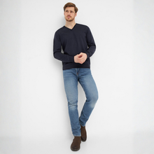 Load image into Gallery viewer, Man wearing a navy sweater and light blue jeans against a white background
