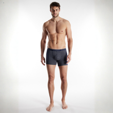 Load image into Gallery viewer, Man wearing black patterned boxer briefs on a white background
