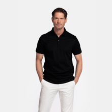 Load image into Gallery viewer, Man wearing a black polo shirt and white pants on a light gray background
