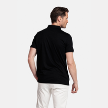 Load image into Gallery viewer, Man wearing a black polo shirt and white pants on a light gray background
