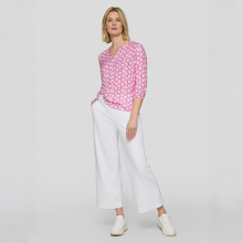Load image into Gallery viewer, Woman wearing a pink patterned blouse and white pants on a light gray background
