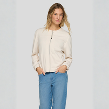 Load image into Gallery viewer, Woman wearing a beige jacket and blue jeans on a plain background
