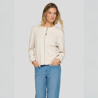 Woman wearing a beige jacket and blue jeans on a plain background