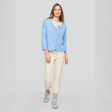 Load image into Gallery viewer, Woman wearing a light blue cardigan and beige pants on a gray background
