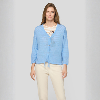 Woman wearing a light blue cardigan over a striped shirt on a plain background