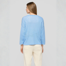 Load image into Gallery viewer, Woman wearing a light blue sweater and white pants on a gray background
