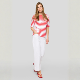 Woman wearing a red and white striped shirt and white pants on a plain background