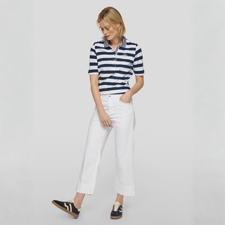Woman wearing a striped shirt and white pants on a plain background