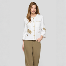 Load image into Gallery viewer, Woman wearing a white blouse with gold accents and brown pants on a gray background
