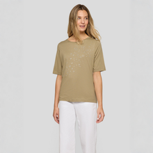 Load image into Gallery viewer, Woman wearing a beige t-shirt and white pants on a light gray background
