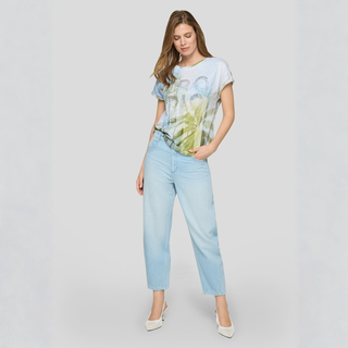 Woman wearing a light blue t-shirt with a palm tree design and light blue jeans on a white background