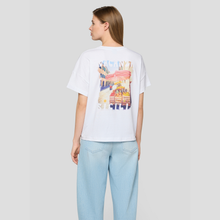 Load image into Gallery viewer, Woman wearing a white t-shirt with a colorful graphic design on a plain background
