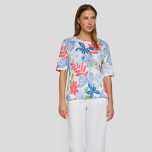 Load image into Gallery viewer, Woman wearing a colorful floral-patterned shirt against a plain background
