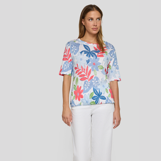 Woman wearing a colorful floral-patterned shirt against a plain background