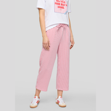 Load image into Gallery viewer, Person wearing a white t-shirt with text and pink checkered pants on a gray background
