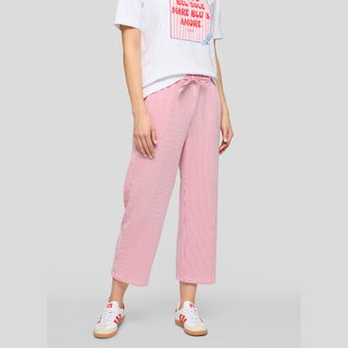 Person wearing a white t-shirt with text and pink checkered pants on a gray background