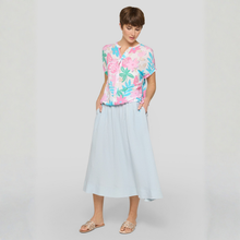 Load image into Gallery viewer, Woman wearing a colorful floral top and light blue skirt on a white background
