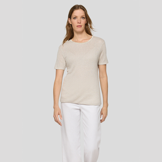 Woman wearing a beige top and white pants on a light gray background