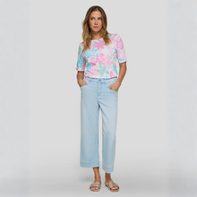 Load image into Gallery viewer, Woman wearing a colorful floral top and light blue jeans on a white background
