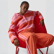 Load image into Gallery viewer, Person wearing a pink and orange striped sweater and pants sitting on a red chair against a white background
