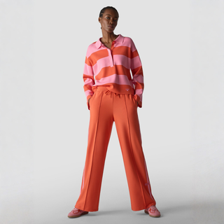 Person wearing a pink and orange striped sweater with matching pants on a light gray background