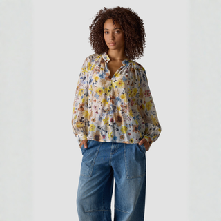 Woman wearing a floral blouse and jeans on a white background