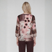 Load image into Gallery viewer, A woman viewed from behind wearing a sheer long-sleeve blouse with an abstract print in pink, brown, and beige, paired with dark brown pants, against a light gray studio background.
