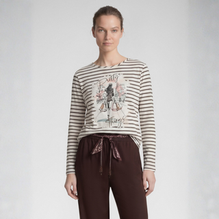 A model wearing a beige and brown striped long-sleeve top with a vintage graphic print on the front, paired with dark brown drawstring pants, against a light gray studio background.