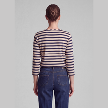 Load image into Gallery viewer, A model shown from the back wearing a beige and navy blue horizontally striped long-sleeve top and dark blue jeans, set against a plain light gray studio background.
