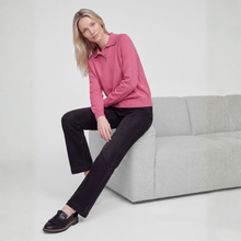 Load image into Gallery viewer, A woman sits on a light gray sofa wearing a pink long-sleeve polo knit top, black pants, and black loafers against a clean white studio background.
