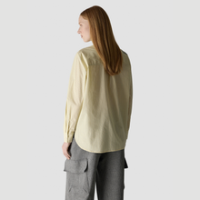Load image into Gallery viewer, A woman with long light brown hair is shown from the back wearing a pale yellow-green striped long-sleeve shirt and gray pinstriped cargo pants, set against a solid light gray background.
