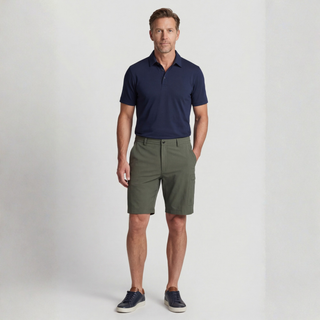 Man wearing a navy polo shirt and green shorts on a light gray background