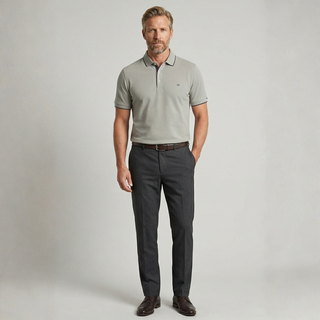 Man wearing a gray polo shirt and dark gray pants against a plain background