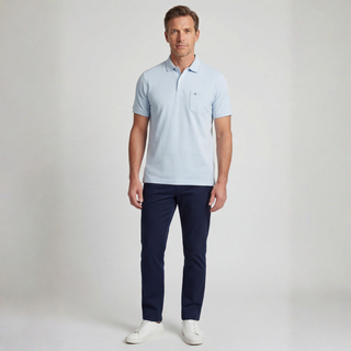 Man wearing a light blue polo shirt and navy pants on a plain background