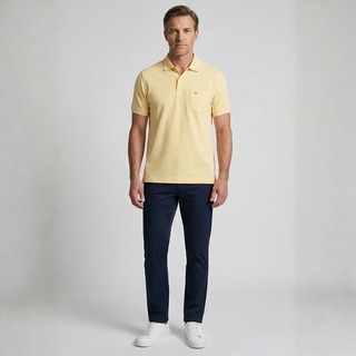 Man wearing a yellow polo shirt and navy pants on a gray background