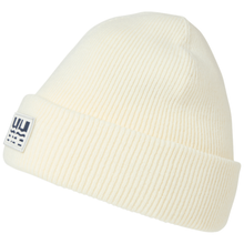 Load image into Gallery viewer, A cream-colored ribbed knit beanie hat with a folded cuff, featuring a small white rectangular patch on the side with a dark blue graphic logo.
