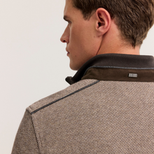Load image into Gallery viewer, Close-up side profile of a man wearing a textured brown and beige herringbone jacket with a dark brown collar, showing the brand tag on the collar.
