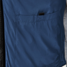 Load image into Gallery viewer, Close-up of a navy blue scrub top showing a front pocket with a black hook-and-loop strap closure.
