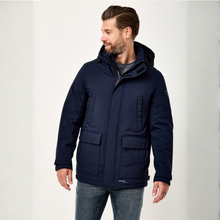 Load image into Gallery viewer, A man wearing a navy blue hooded winter jacket with front flap pockets, shown from the waist up against a plain light background.
