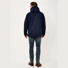 Load image into Gallery viewer, A man viewed from behind wearing a navy blue hooded jacket, blue jeans, and brown shoes, standing against a plain off-white studio background.
