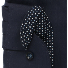Load image into Gallery viewer, Close-up of a navy blue tailored garment, likely a jacket or coat, featuring a buttoned flap pocket and a matching navy necktie with a white and light blue geometric pattern.
