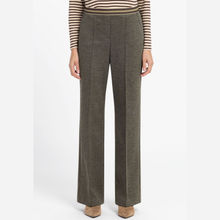Load image into Gallery viewer, A model is shown from the chest down wearing high-waisted, wide-leg trousers in a textured olive green fabric, paired with a striped long-sleeve top and tan heels, against a plain white studio background.
