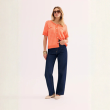 Load image into Gallery viewer, Woman wearing an orange checkered shirt and blue jeans on a white background
