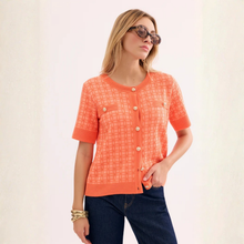 Load image into Gallery viewer, Woman wearing an orange checkered blouse and sunglasses on a light background
