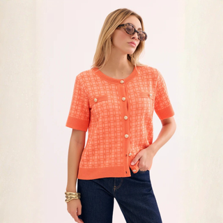 Woman wearing an orange checkered blouse and sunglasses on a light background