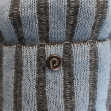 Load image into Gallery viewer, Close-up of a striped knit garment in light blue and dark gray, featuring a small round dark brown button with a white embroidered monogram.
