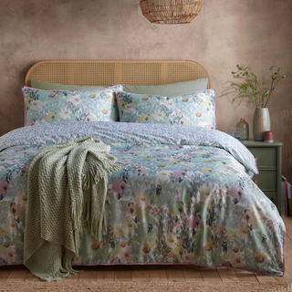 Floral bedding set on a bed with a woven headboard in a bedroom setting.