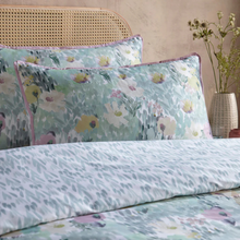Load image into Gallery viewer, Floral patterned bedding set on a bed with a woven headboard and vase in the background.
